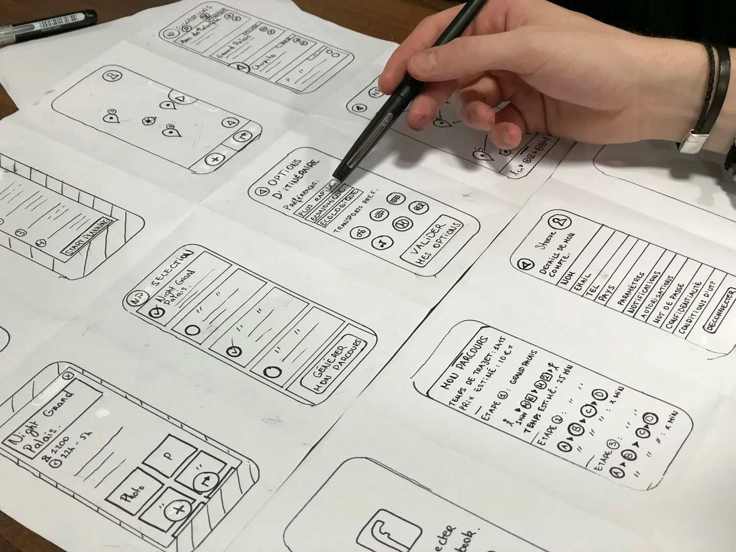 Eine Hand zeichnet auf Papier Entwürfe für Handybildschirme