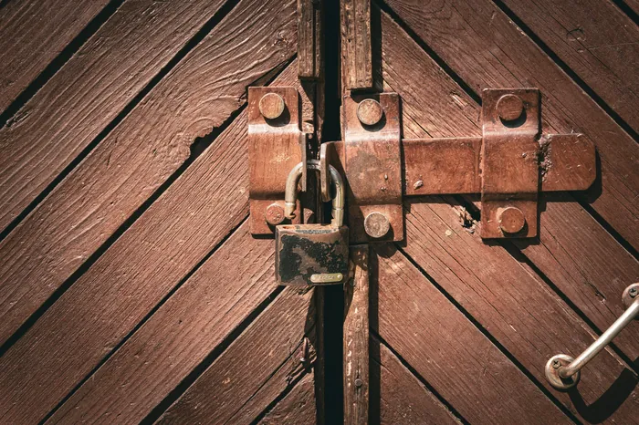 Eine Holztür, mit Riegel und Vorhängeschloss gesichert